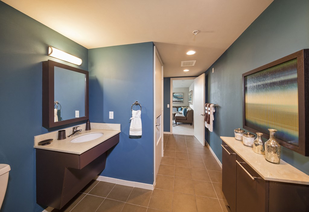A bathroom with blue walls and brown furniture.