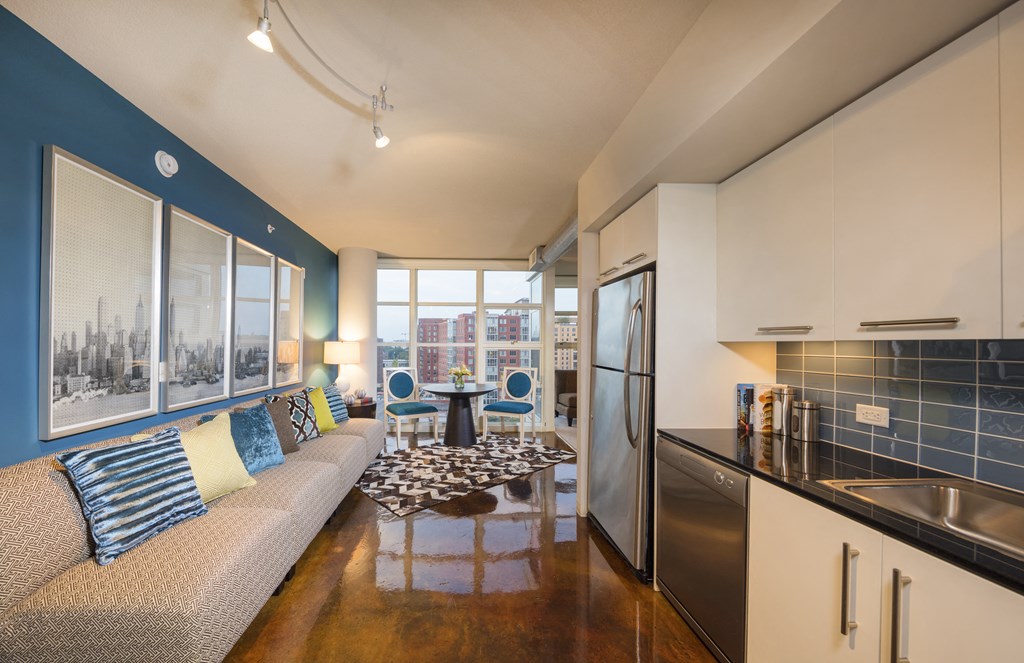 A kitchen with a refrigerator, sink, and a couch with pillows.