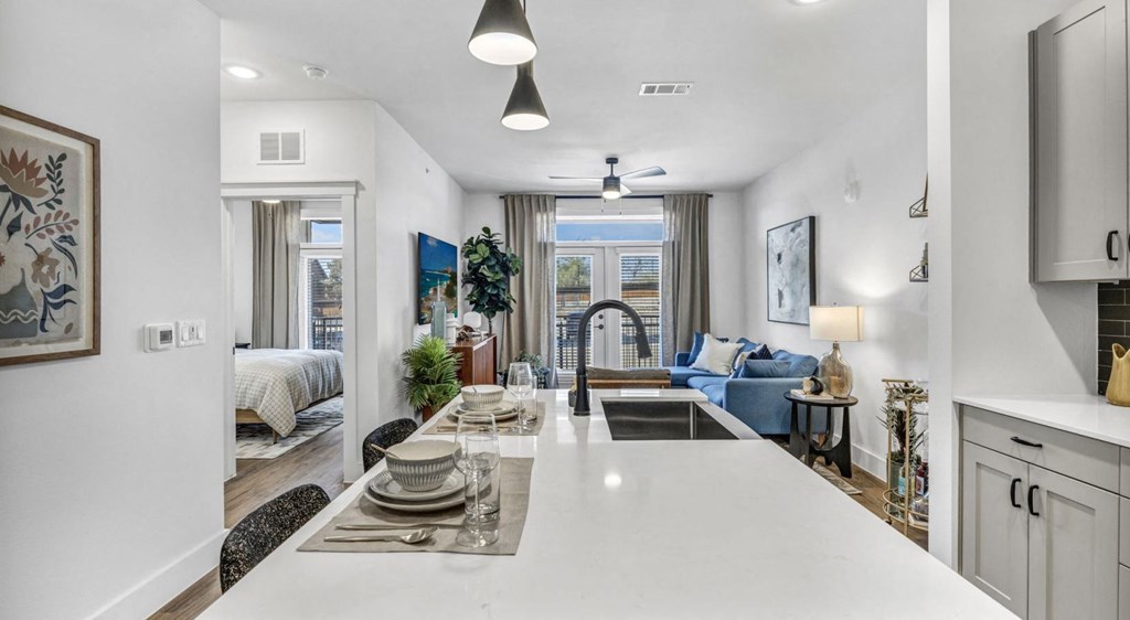 a kitchen with a white counter top next to a living room