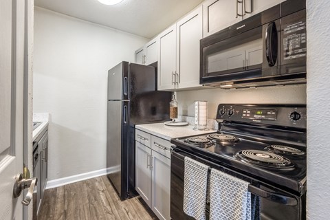 A black refrigerator and microwave in a kitchen with a stove.