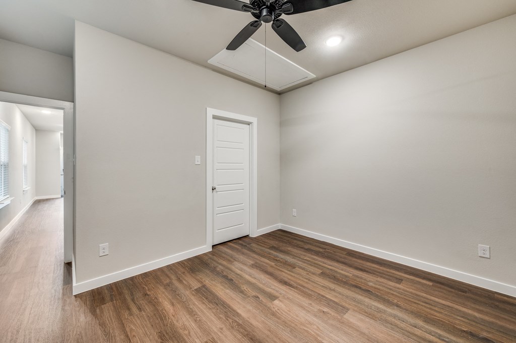 A room with a ceiling fan and wooden flooring.