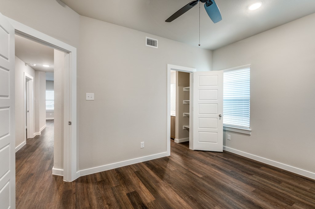 A room with a ceiling fan and wooden floors.