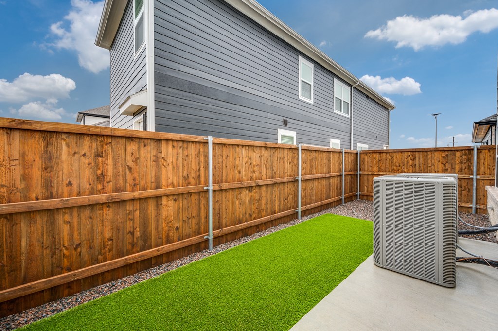 A backyard with a wooden fence and a green lawn.