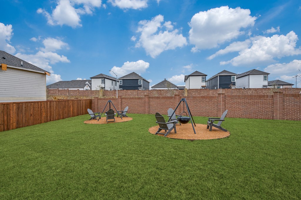 A backyard with a lawn and a swing set.