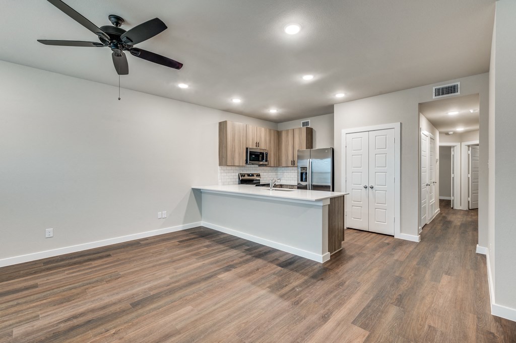 A spacious kitchen with a ceiling fan and wooden flooring.
