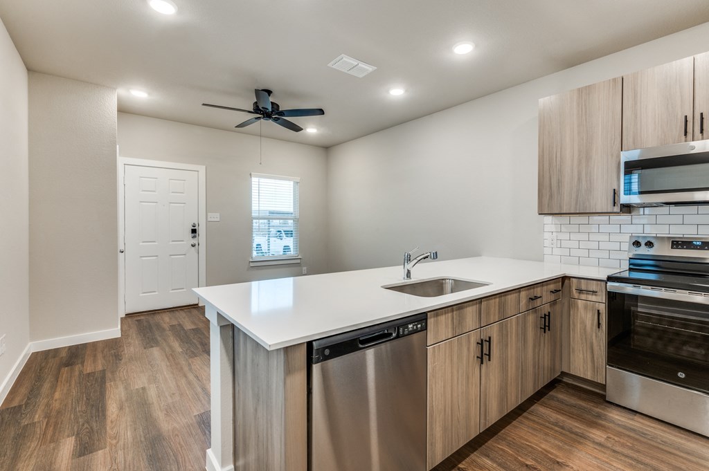A modern kitchen with wooden floors and stainless steel appliances.
