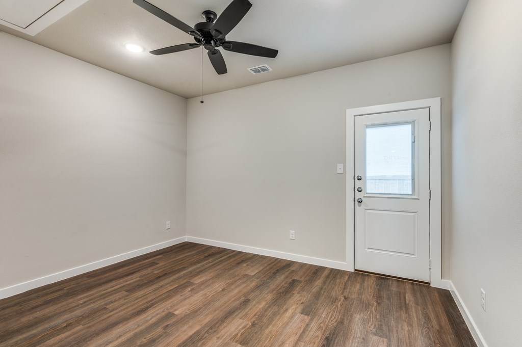 A room with a ceiling fan and a door.