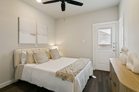 A bedroom with a bed, a ceiling fan, and a wooden dresser.