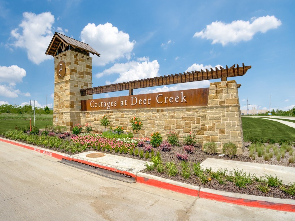 A sign for Cottages at Deer Creek stands in front of a road.