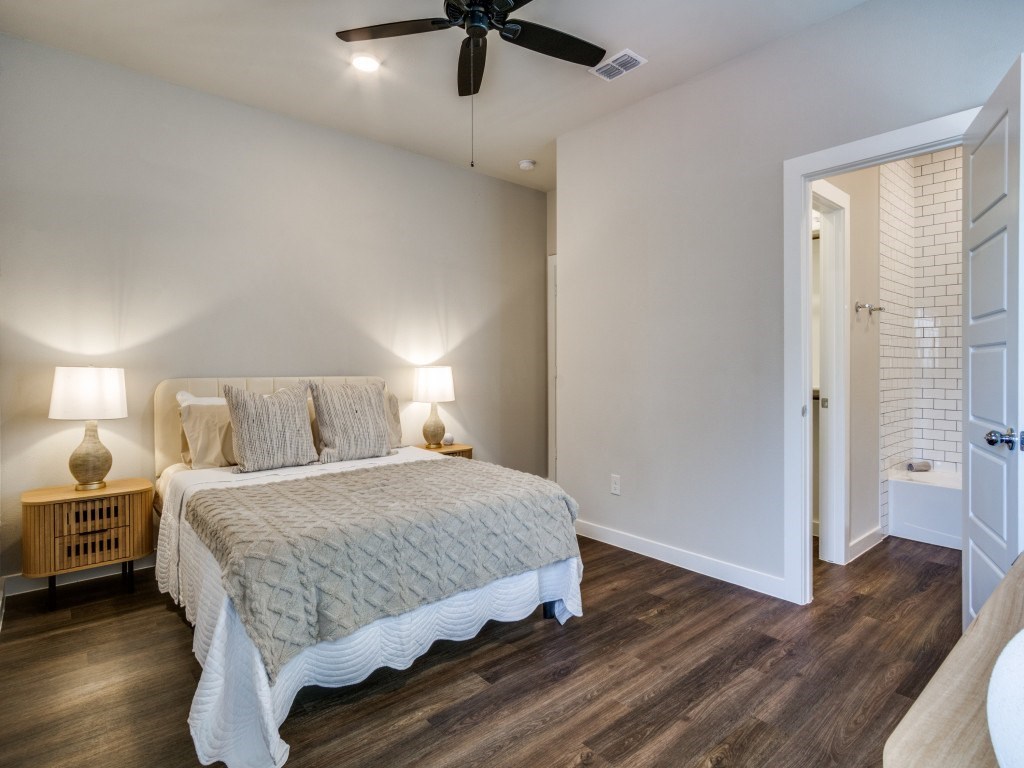 A bedroom with a bed, two lamps, and a ceiling fan.