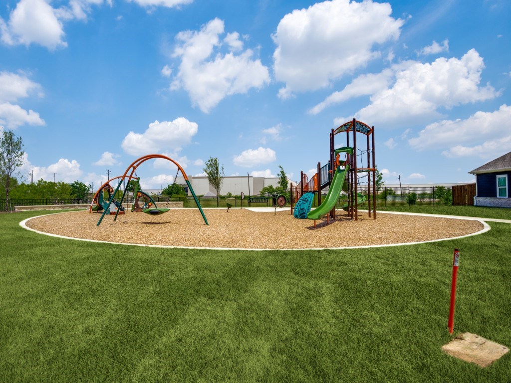 A playground with a green slide and a red swing set.