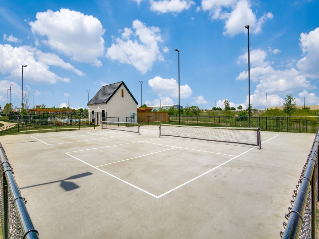 A tennis court with a small building in the background.