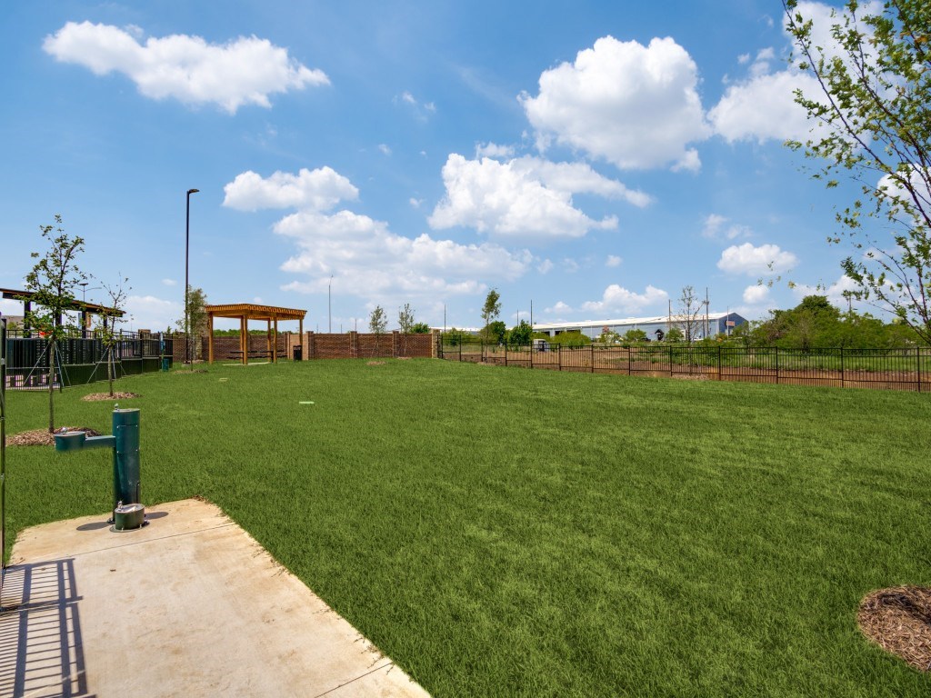 A large grassy field with a wooden structure in the distance.