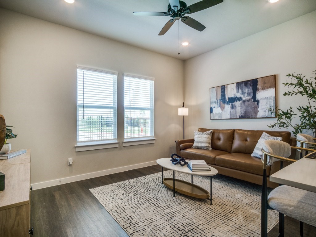 A living room with a brown couch and a ceiling fan.