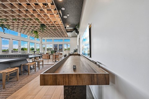 A long wooden table is in the middle of a room with a pool table.