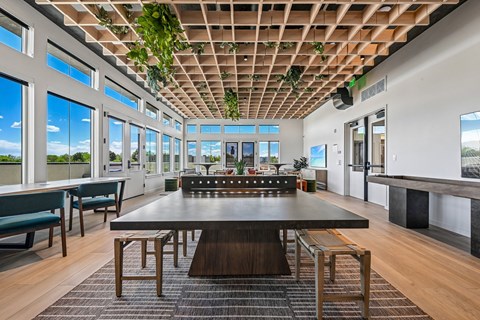 A conference room with a long table and chairs, a whiteboard, and a view of the sky through the windows.