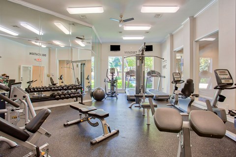 A gym with a variety of equipment including weights, machines, and a bench.