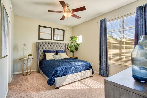 A bedroom with a bed, a ceiling fan, and a nightstand.