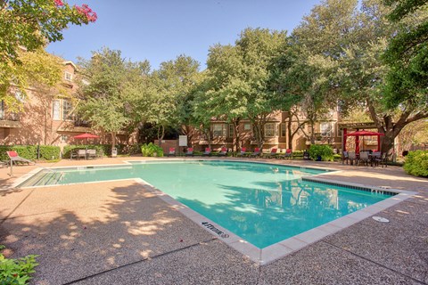 A pool surrounded by trees and buildings.