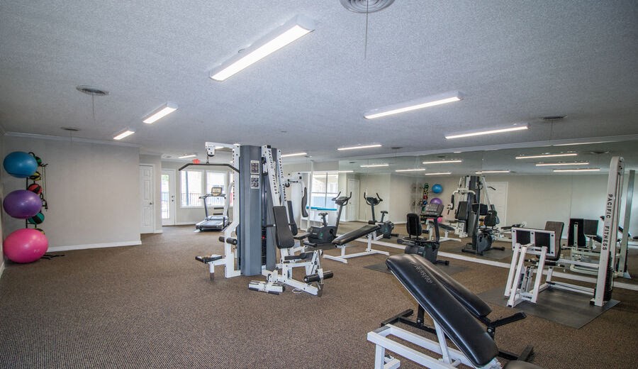 a gym with cardio equipment and weights on the floor