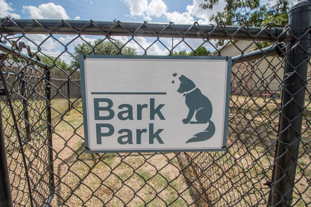 a bark park sign on a chain link fence