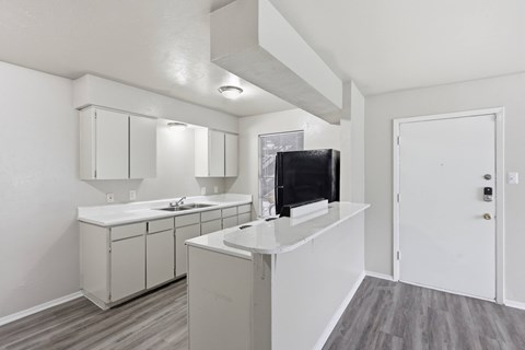 A kitchen with white cabinets and a black television.