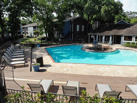 A pool surrounded by chairs and trees.