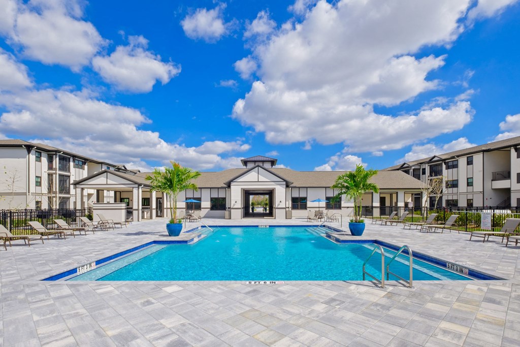 a large swimming pool with apartments in the background