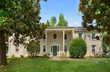 a white house with a green lawn and trees
