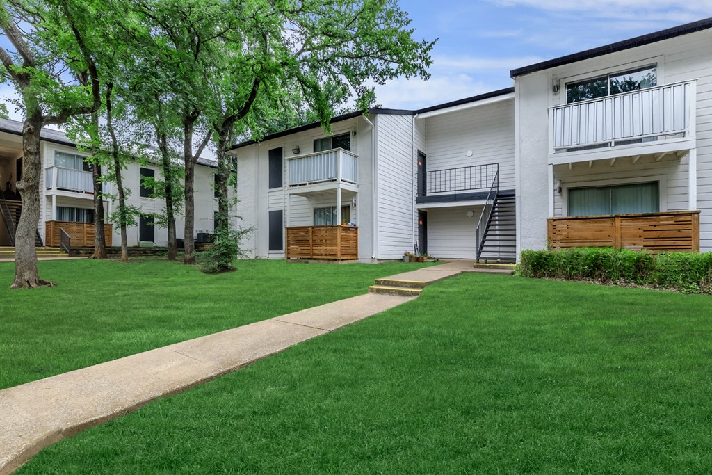 a grassy area with trees and buildings in the background