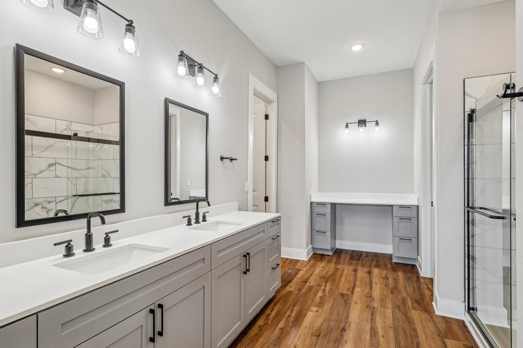 A bathroom with a white counter top and a wooden floor.