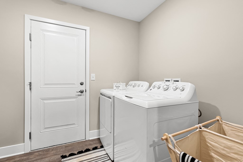 a utility room with a washer and dryer and a door to a bathroom