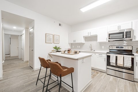 a kitchen with white cabinets and a white counter top with two chairs