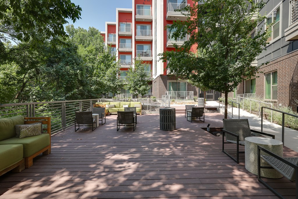 A wooden deck with chairs and a table in the middle of it.