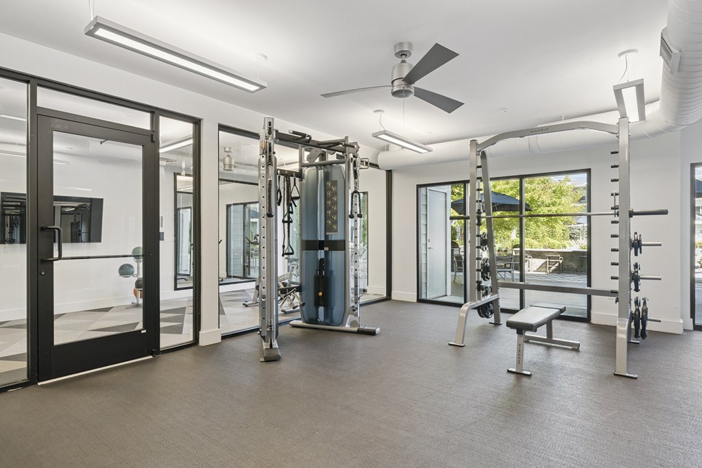 A gym with a variety of equipment including a squat rack, bench, and weights.