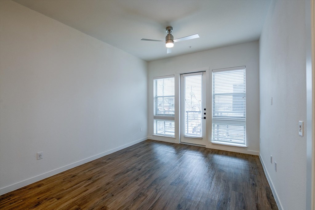 an empty living room with white walls and wood floors and a ceiling fan