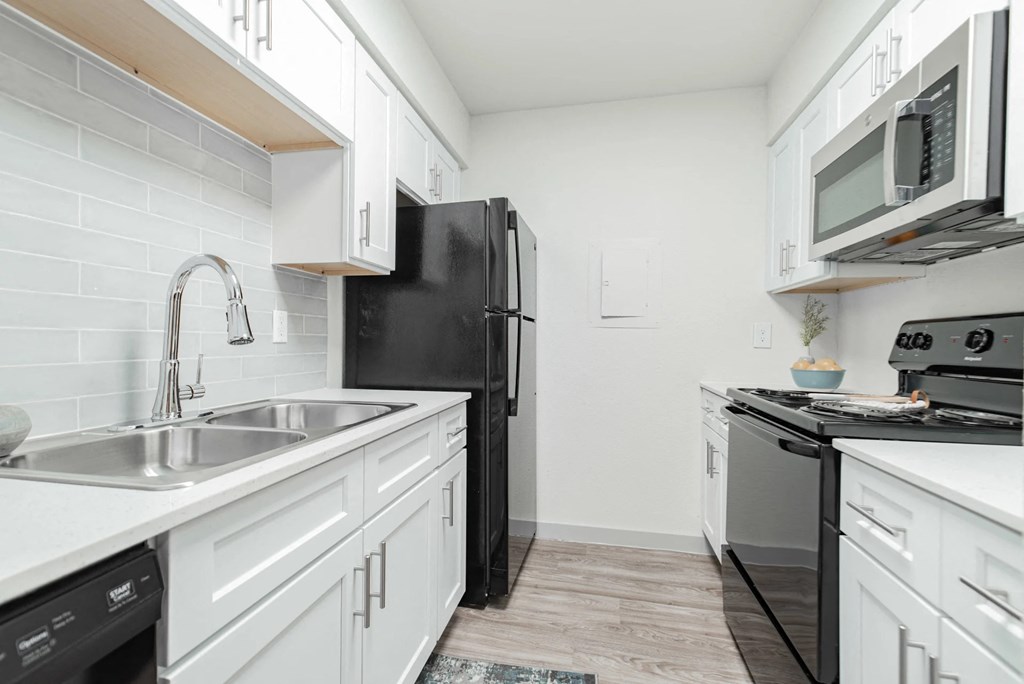 A kitchen with black appliances and white cabinets.