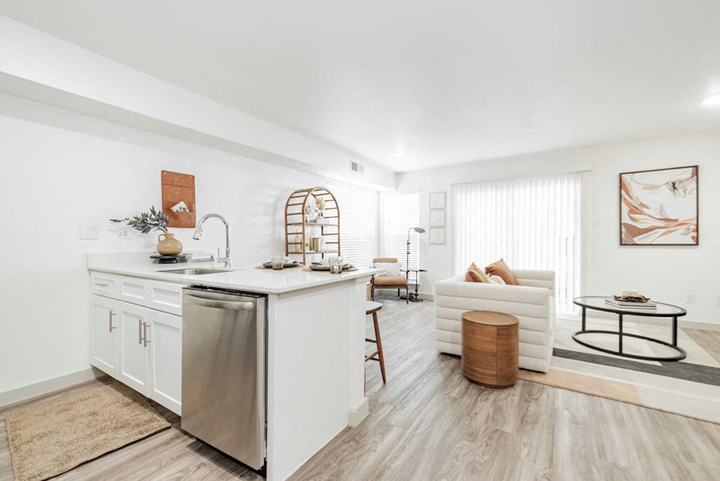 A modern kitchen with white cabinets and a wooden floor.