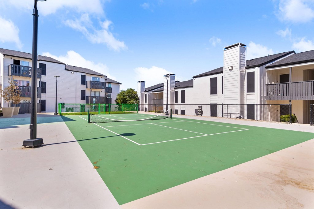 an outdoor tennis court with apartments in the background