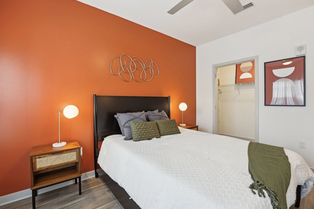 A bedroom with a bed, nightstand, and a ceiling fan.