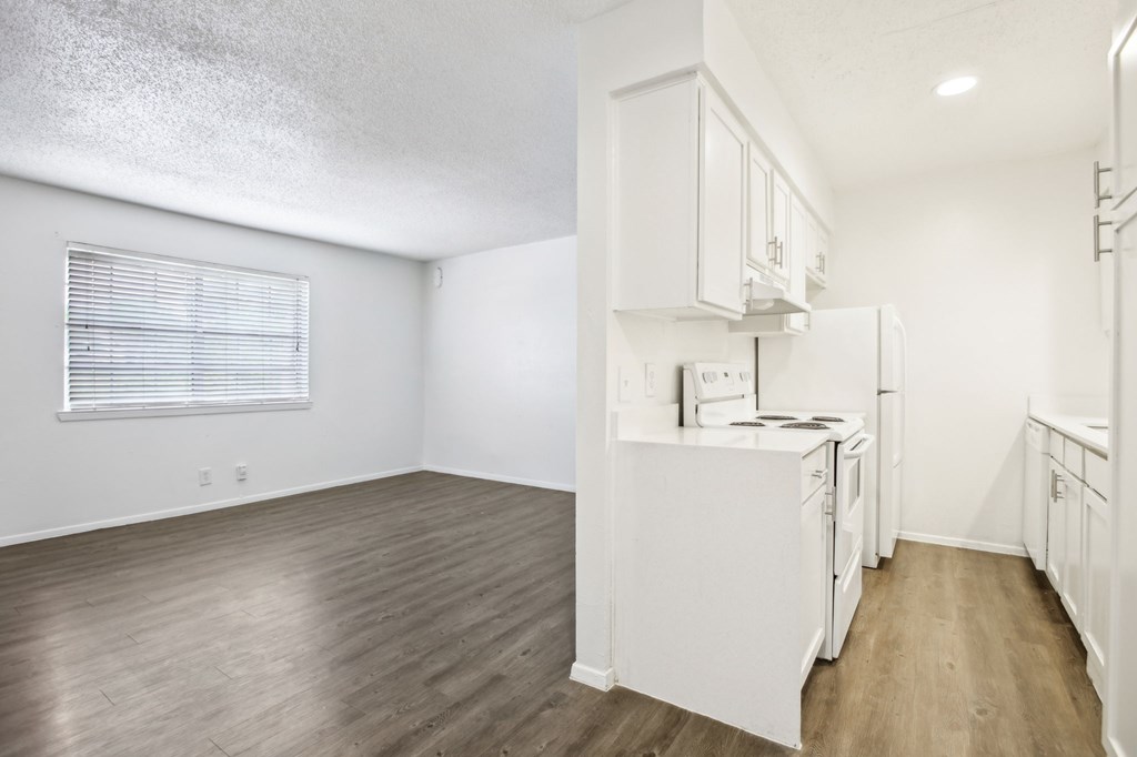 A white kitchen with wood floors and white appliances.