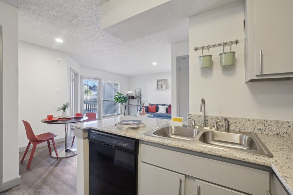 A modern kitchen with a red chair and a dishwasher.