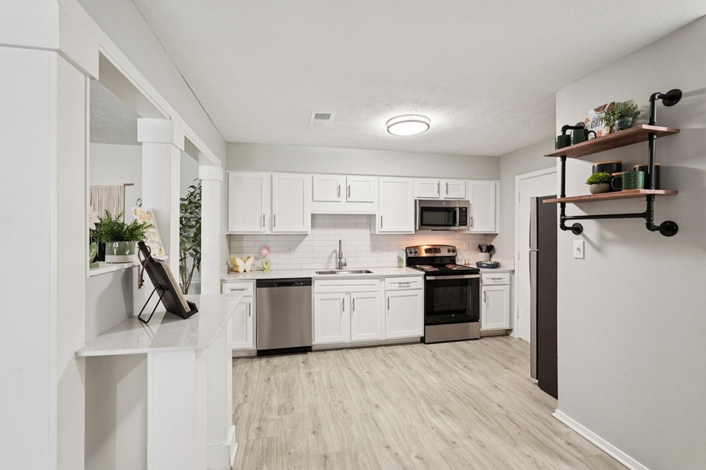 A modern kitchen with white cabinets and stainless steel appliances.