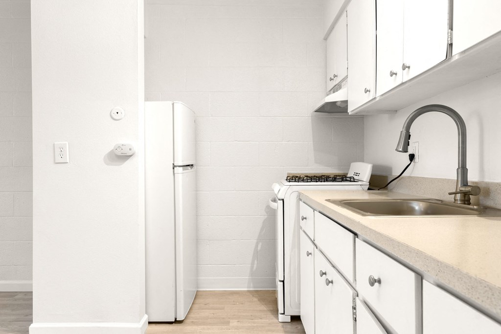 a kitchen with white cabinets and a sink and a refrigerator