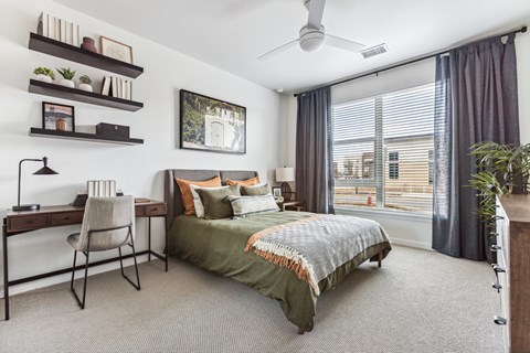 A bedroom with a bed, desk, and chair.