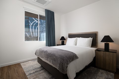 A bedroom with a large bed and two lamps.
