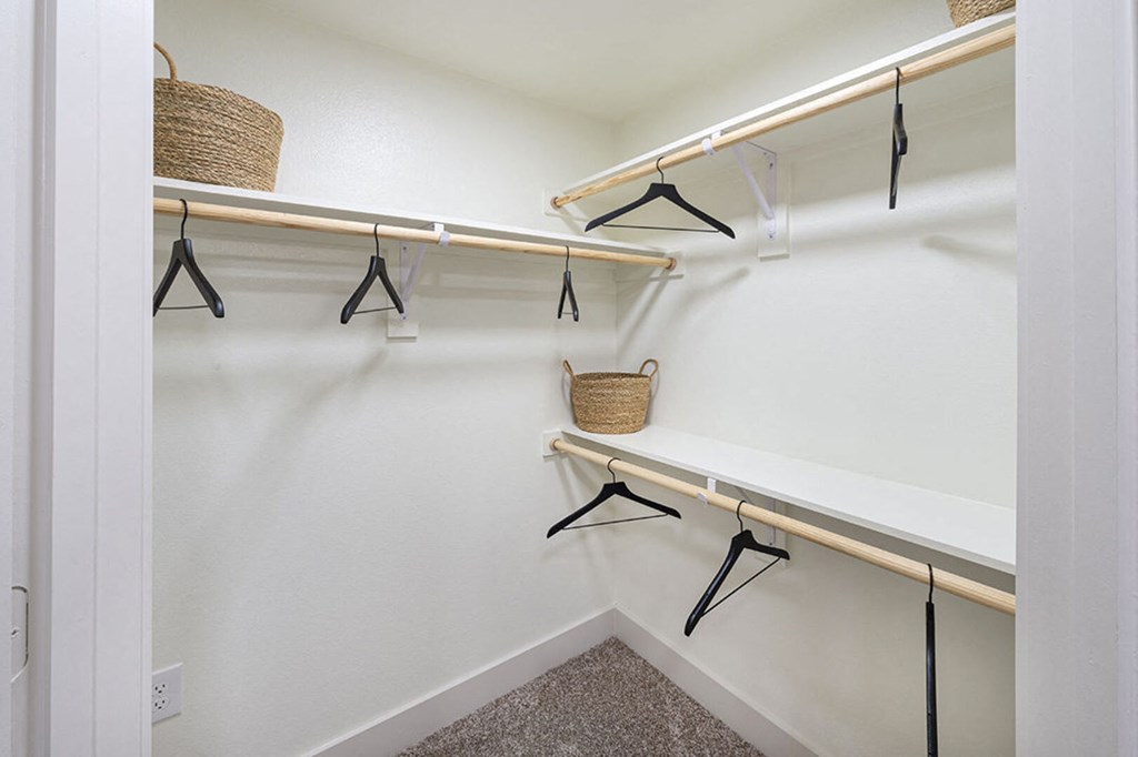 a walk in closet with hanging racks and a basket