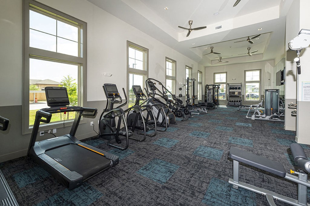 the fitness center has cardio equipment and windows at the estates apartments
