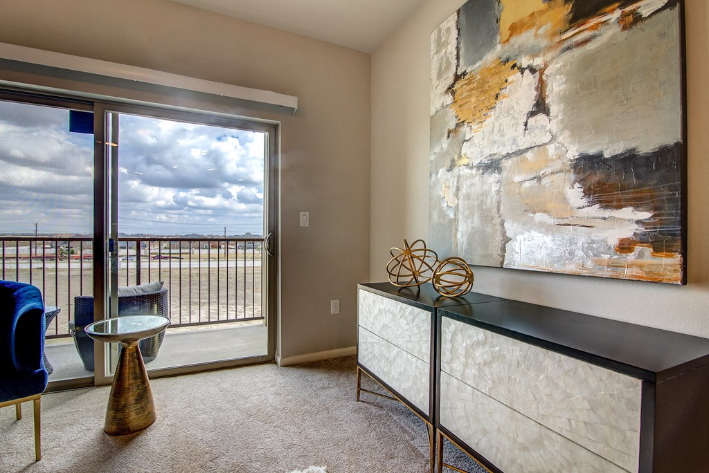 a living room with a large painting on the wall and a glass door leading to a balcony