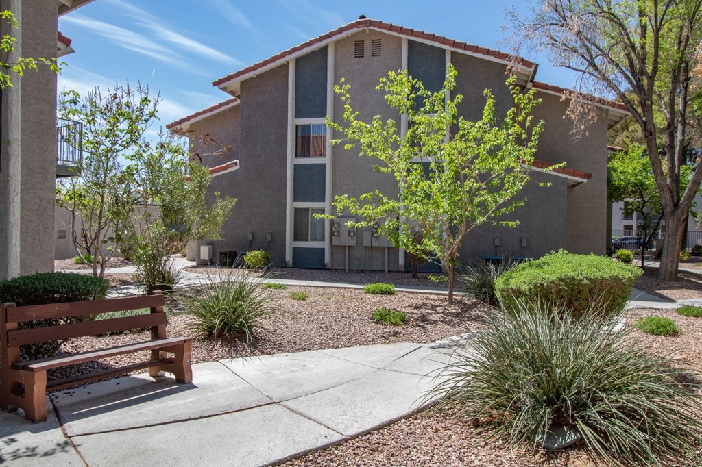 a bench in front of a building with trees and plants
